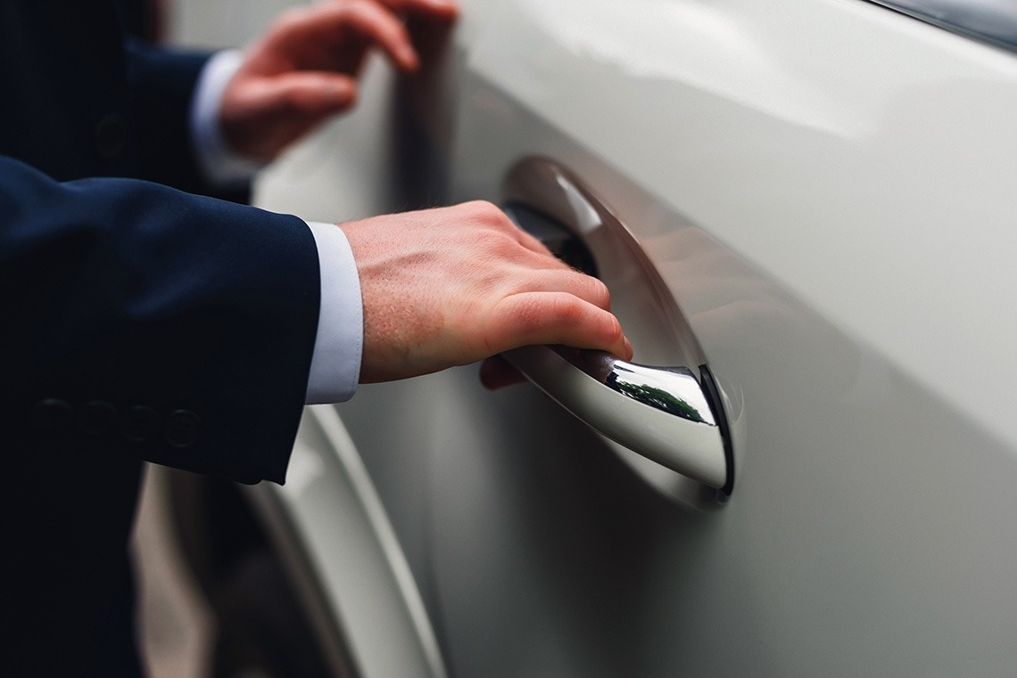 un hombre en un traje abre la puerta de un coche