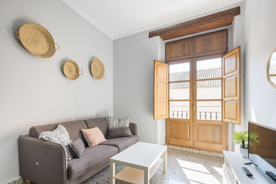 Acogedora sala de estar con sofá, mesa de centro y puertas de madera, Macflats Valencia | Web oficial.