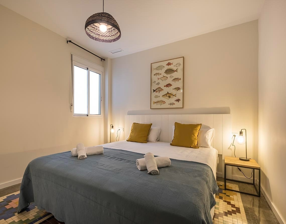 Dormitorio moderno Macflats Valencia con cama confortable y cuadro de peces. ¡Reserva ya!