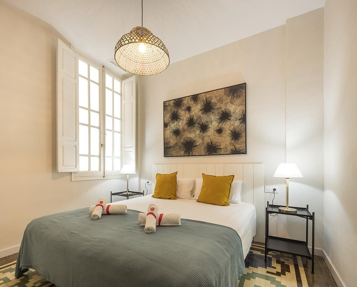 Habitación luminosa con cama doble, arte mural y ventana en Macflats Ayuntamiento | Web Oficial