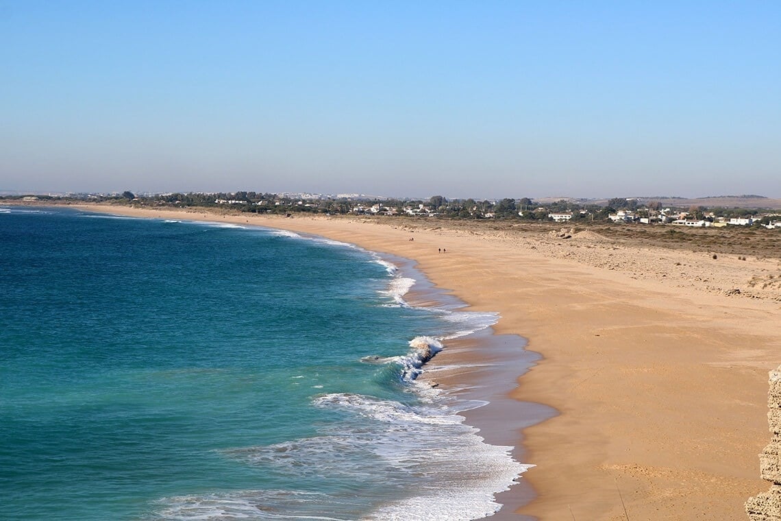 una playa de arena y olas en un día soleado