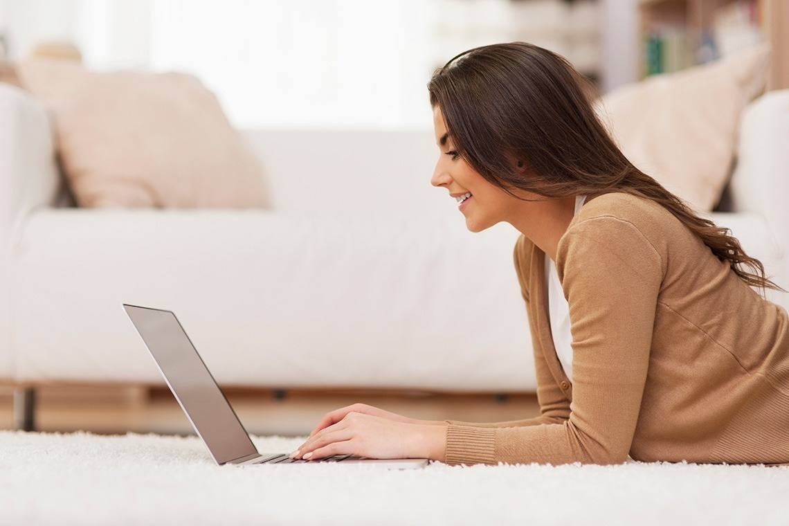 una mujer está acostada en el suelo usando una computadora portátil