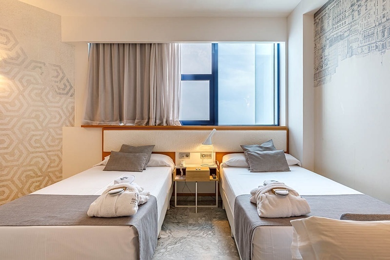 una habitación de hotel con dos camas y una ventana