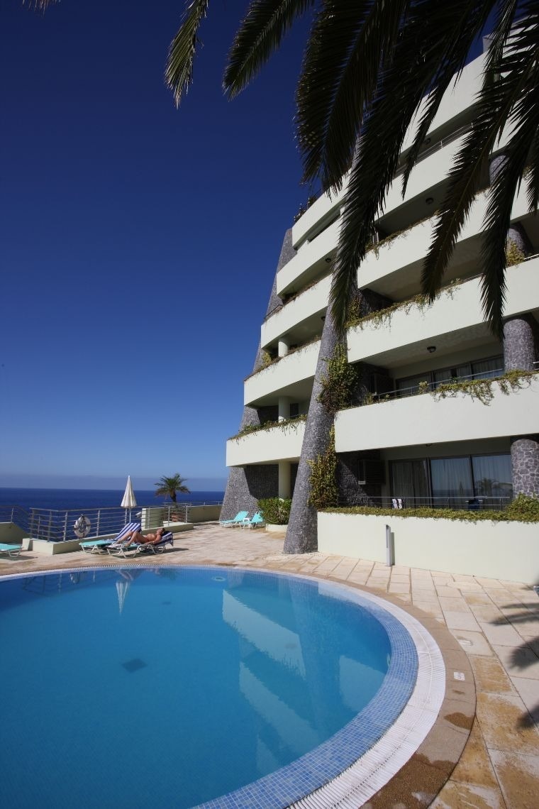 uma grande piscina em frente a um prédio com vista para o oceano