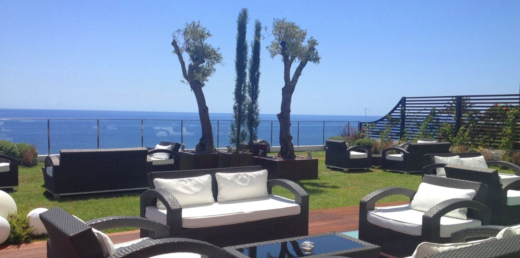 uma varanda com móveis e árvores com vista para o oceano