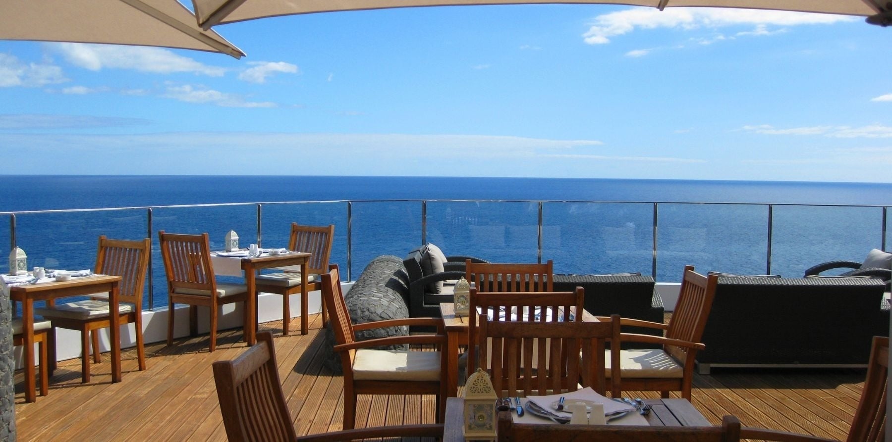 mesas e cadeiras em um deck de madeira com vista para o oceano