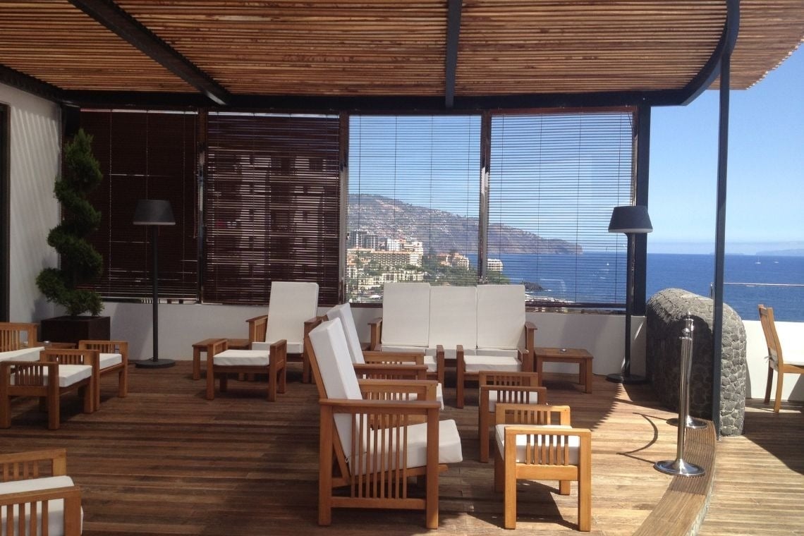 uma varanda com cadeiras e mesas com vista para o oceano