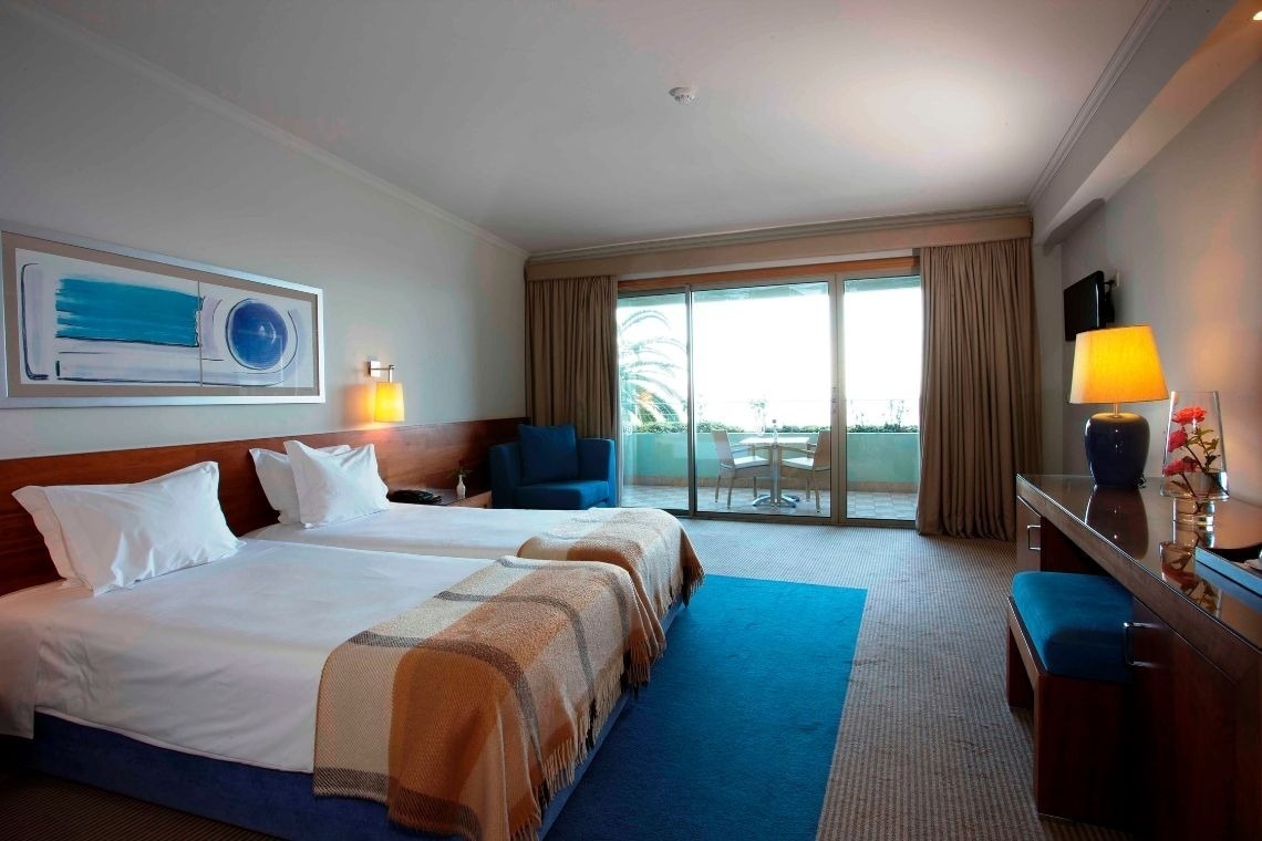 a hotel room with two beds and a sliding glass door