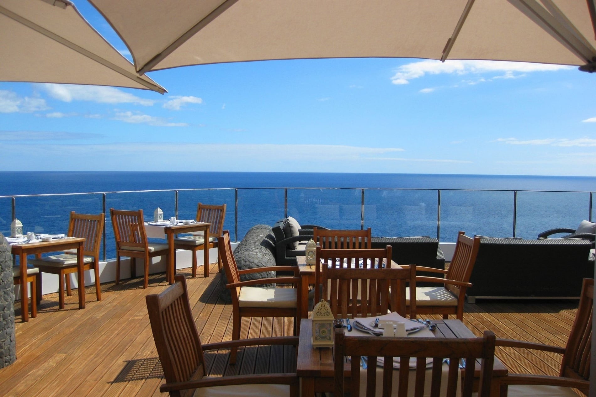 mesas e cadeiras em um deck de madeira com vista para o oceano