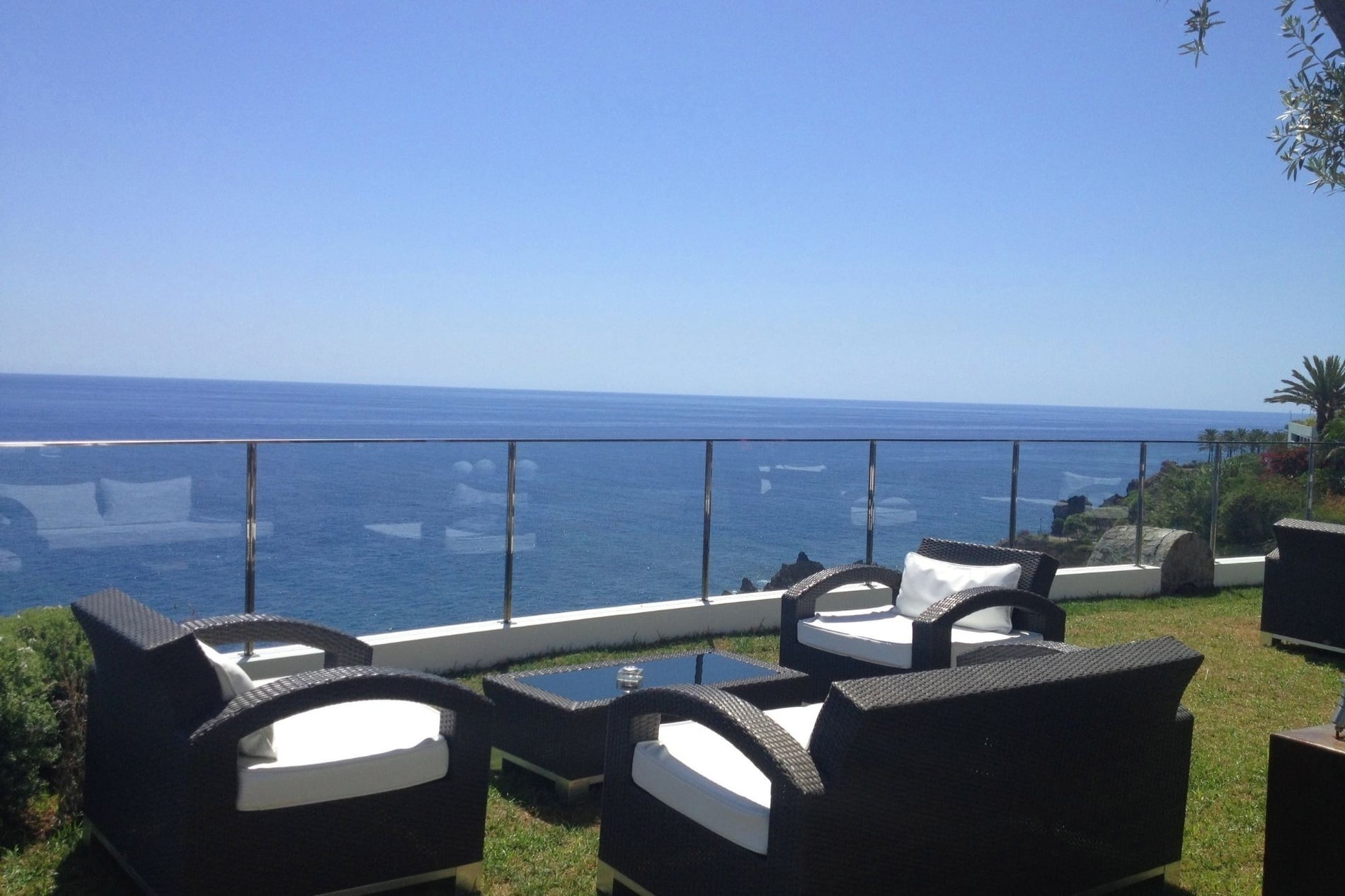 uma varanda com cadeiras e uma mesa com vista para o oceano