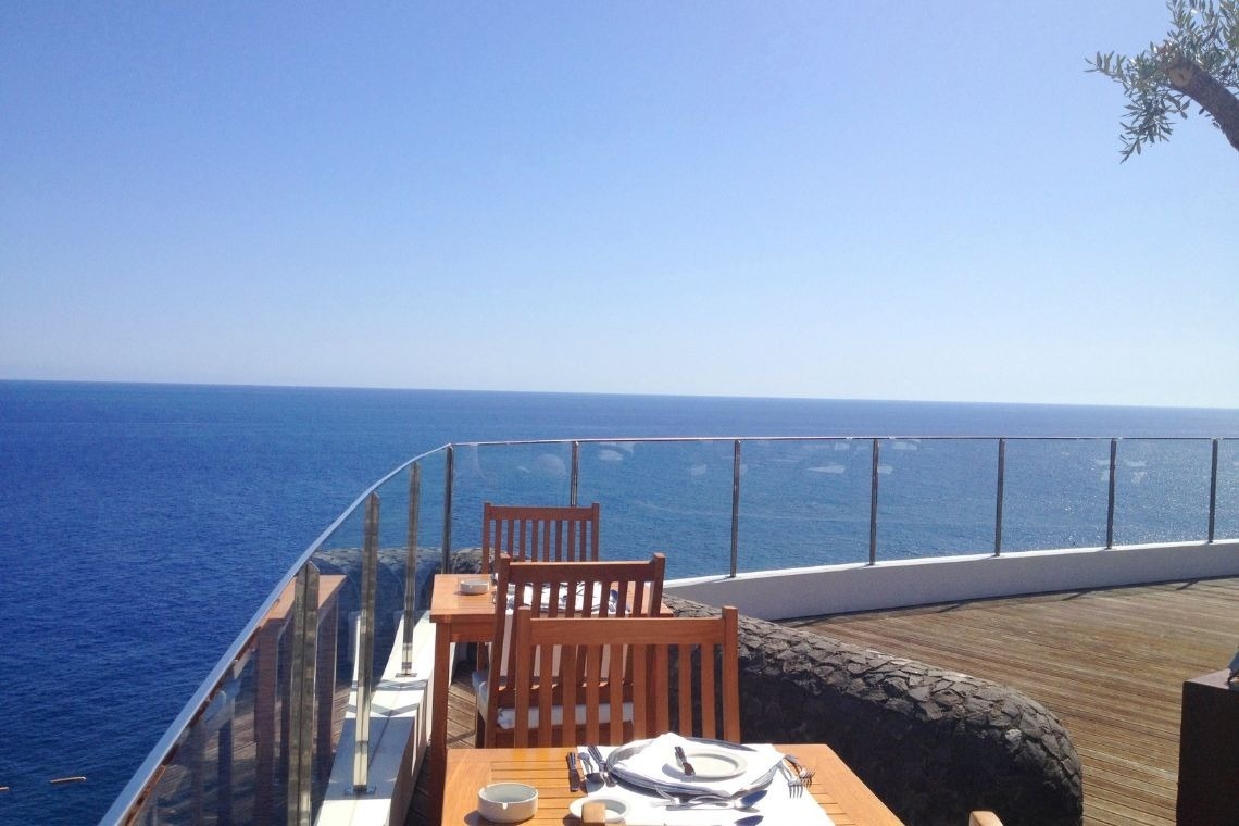 uma mesa e cadeiras em um deck com vista para o oceano