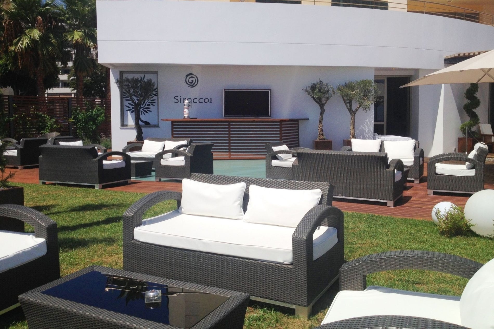 uma área de estar ao ar livre com sofás e cadeiras em frente ao siroccoi