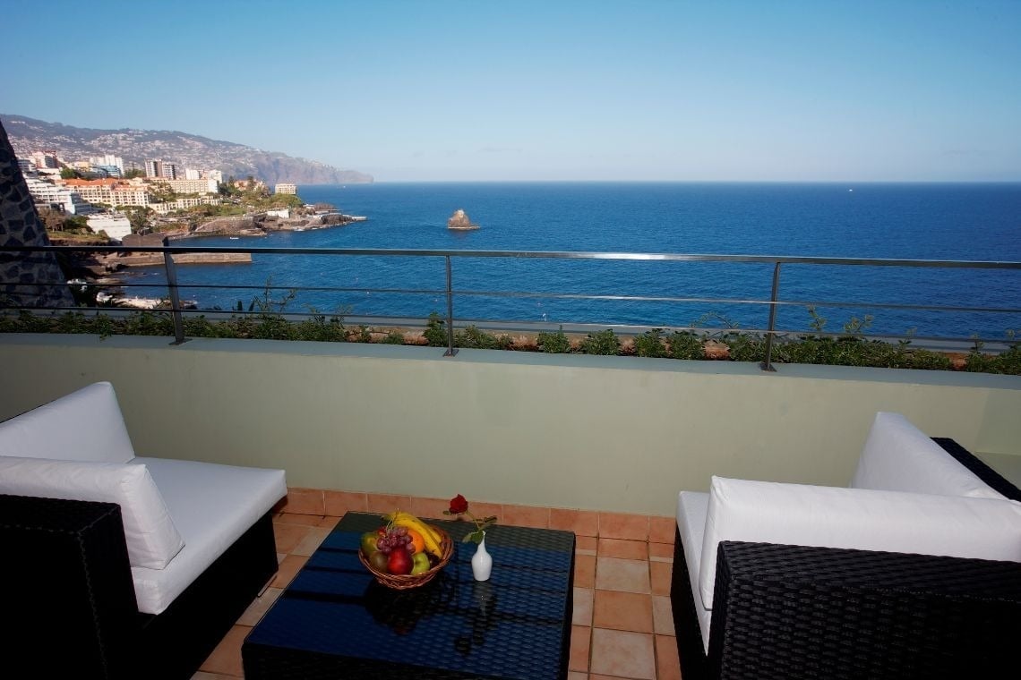 uma mesa com comida e bebidas em uma varanda com vista para uma piscina