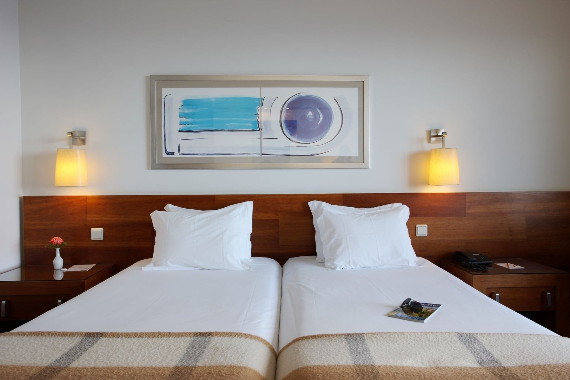 um quarto de hotel com duas camas e uma pintura sobre a cabeceira