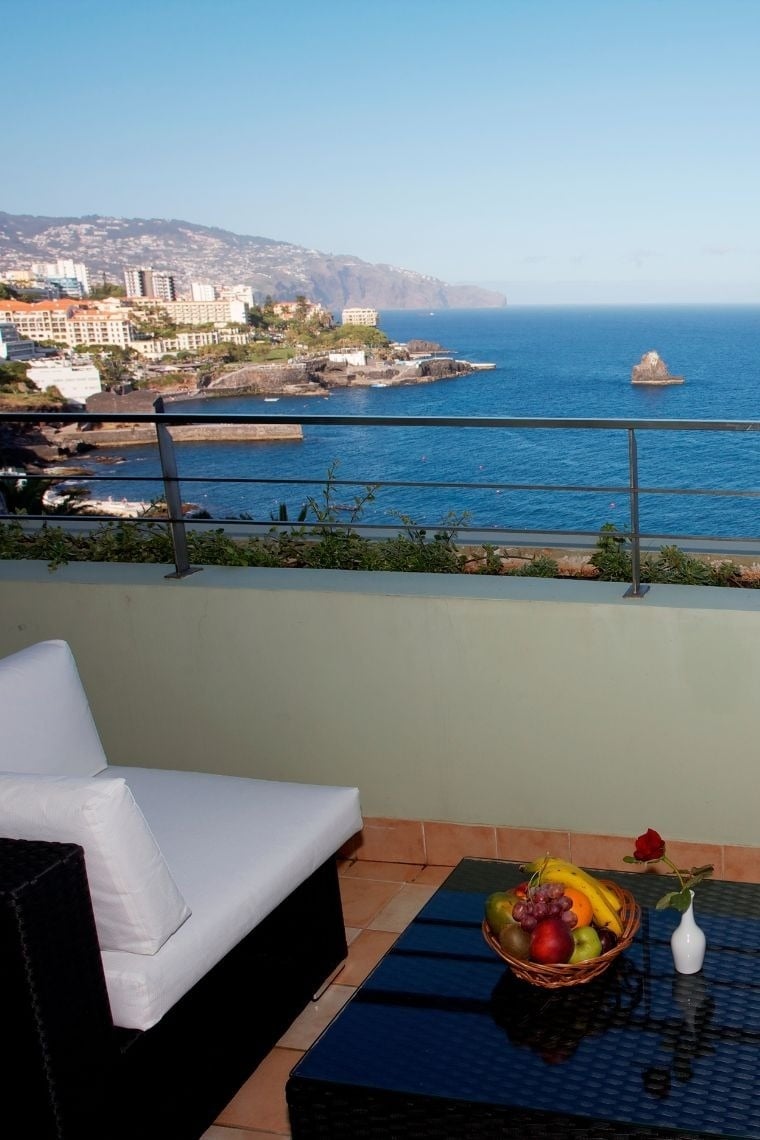 uma varanda com vista para o oceano e uma mesa de frutas