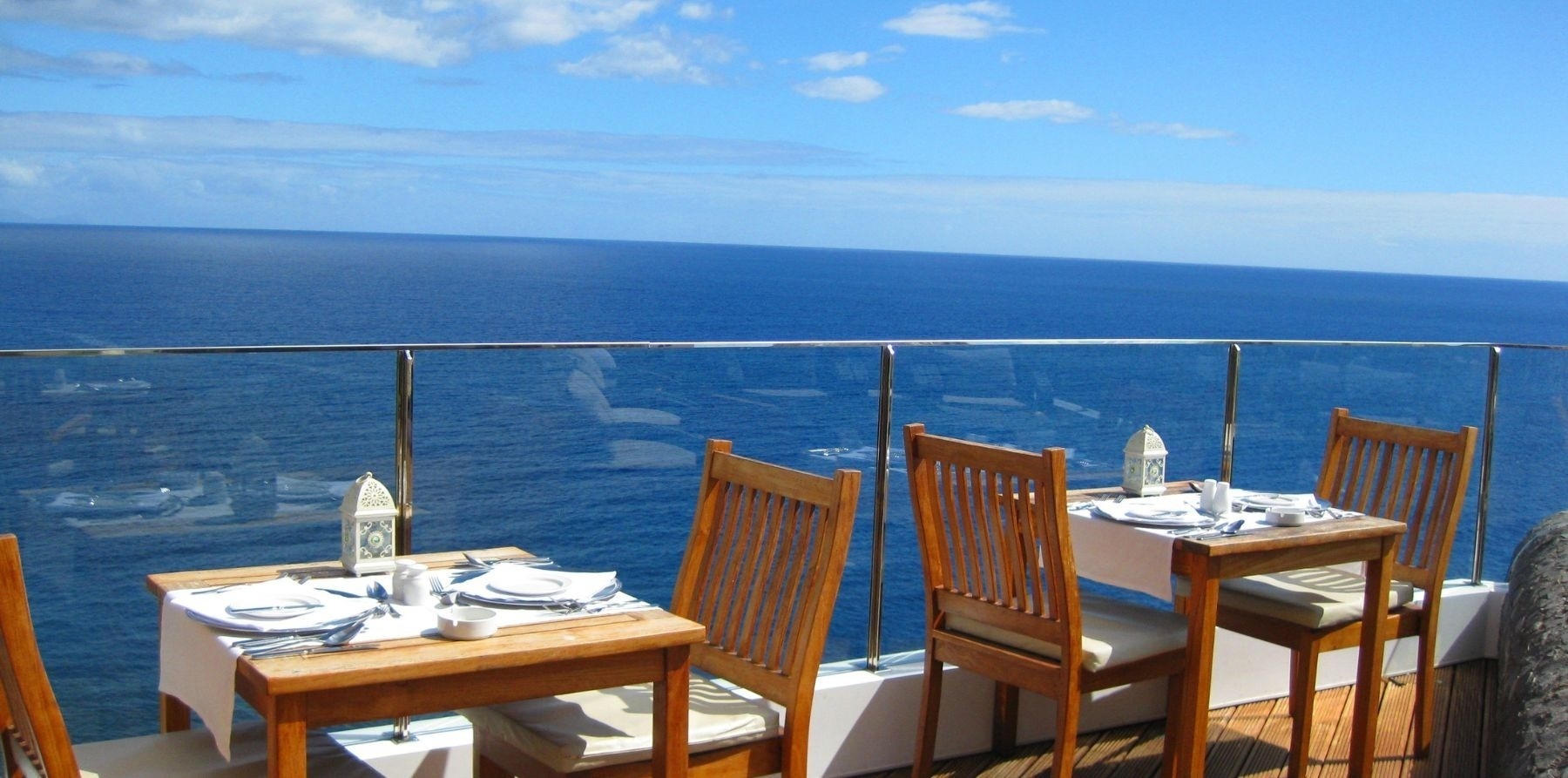 mesas e cadeiras em uma varanda com vista para o oceano