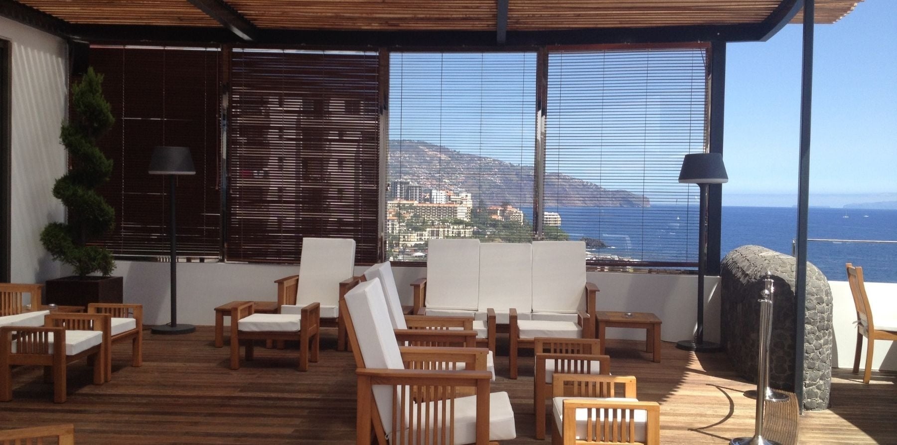 uma varanda com cadeiras e mesas com vista para o oceano