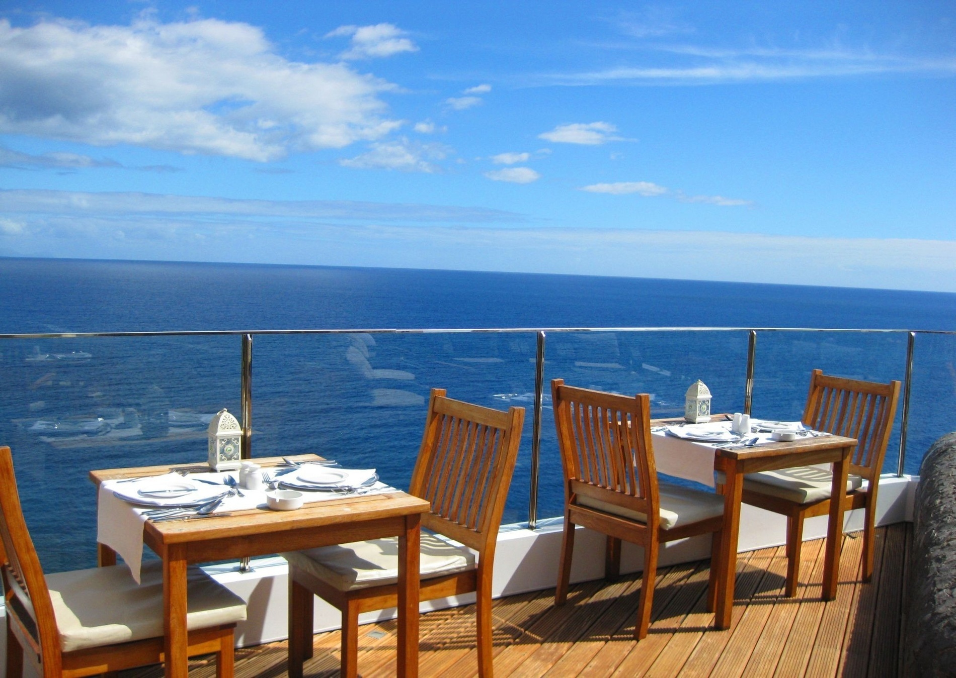 tables and chairs on a balcony overlooking the ocean