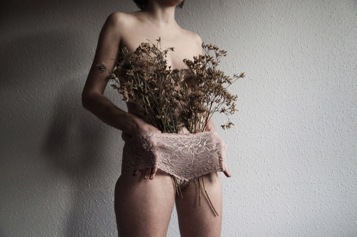 Artistic image of a woman holding dried flowers and lace. Maisonnave Hotel.