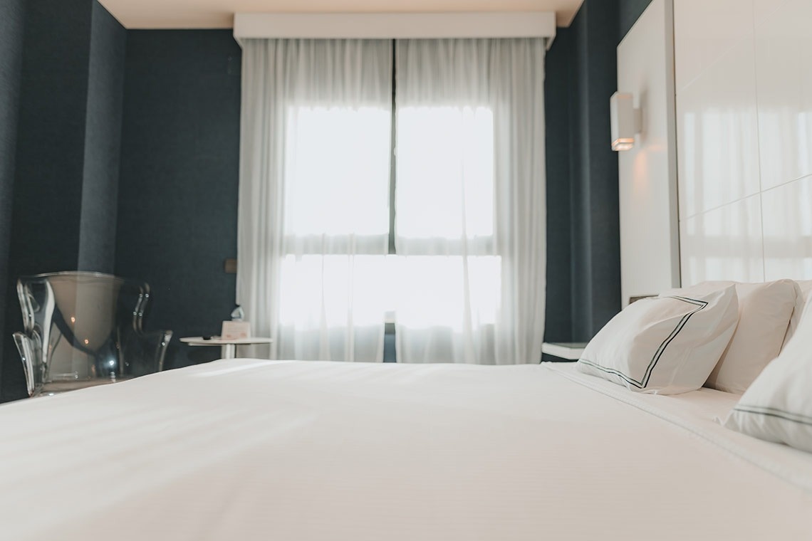 una habitación con una cama y una ventana con cortinas blancas