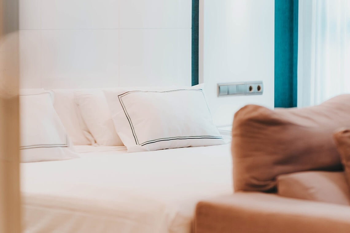 una cama con almohadas blancas y un sofá marrón