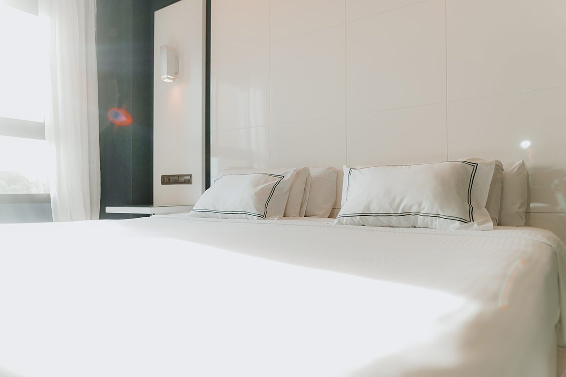 una cama con sábanas blancas y almohadas en una habitación