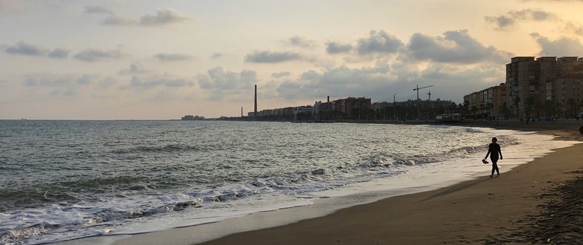 un hombre camina por la playa al atardecer