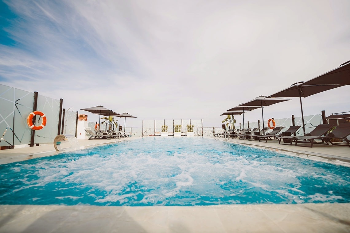 a swimming pool with chairs and umbrellas around it