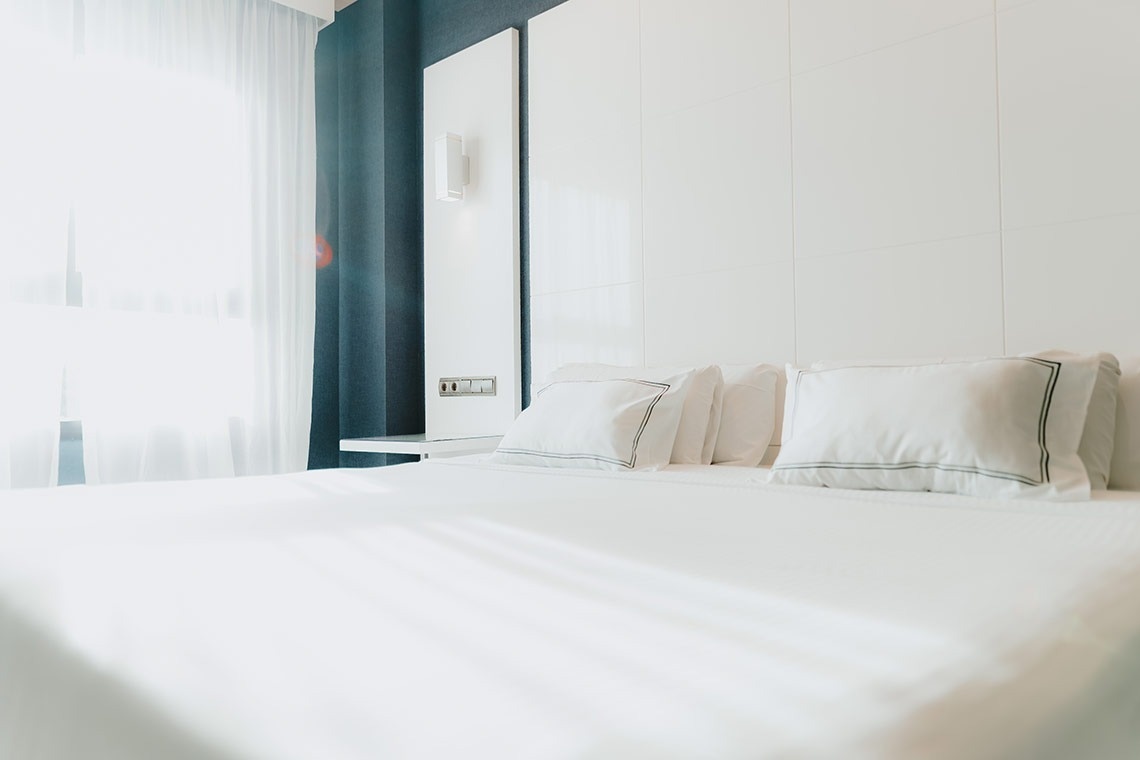 una cama con sábanas blancas y almohadas en una habitación