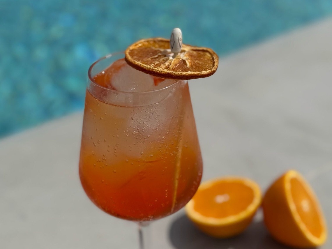 a drink in a wine glass with an orange slice on top