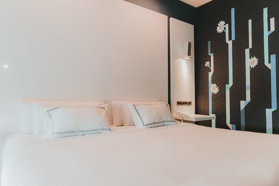 una cama con almohadas blancas y una pared con flores pintadas