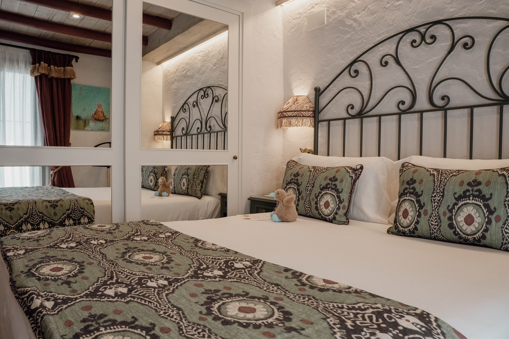 KAIZEN: Malvasia King bed with decorative headboard and teddy bear.