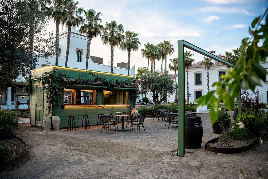 a woman sits at a table in front of a green building