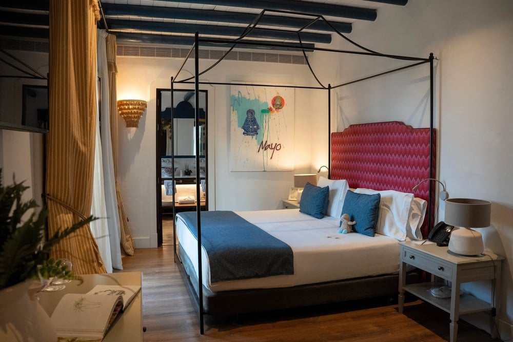 una habitación con una cama con dosel y una pintura en la pared que dice mayo