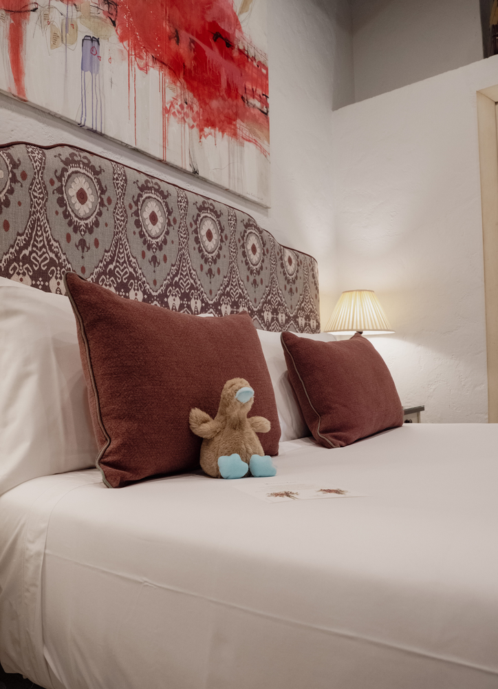 KAIZEN: Malvasia Suite featuring a king bed, decorative headboard, and built-in closet.