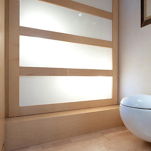 Salle de bain d'hôtel moderne avec toilettes ovales et porte coulissante translucide. Suites del Mar Fenals Apartments