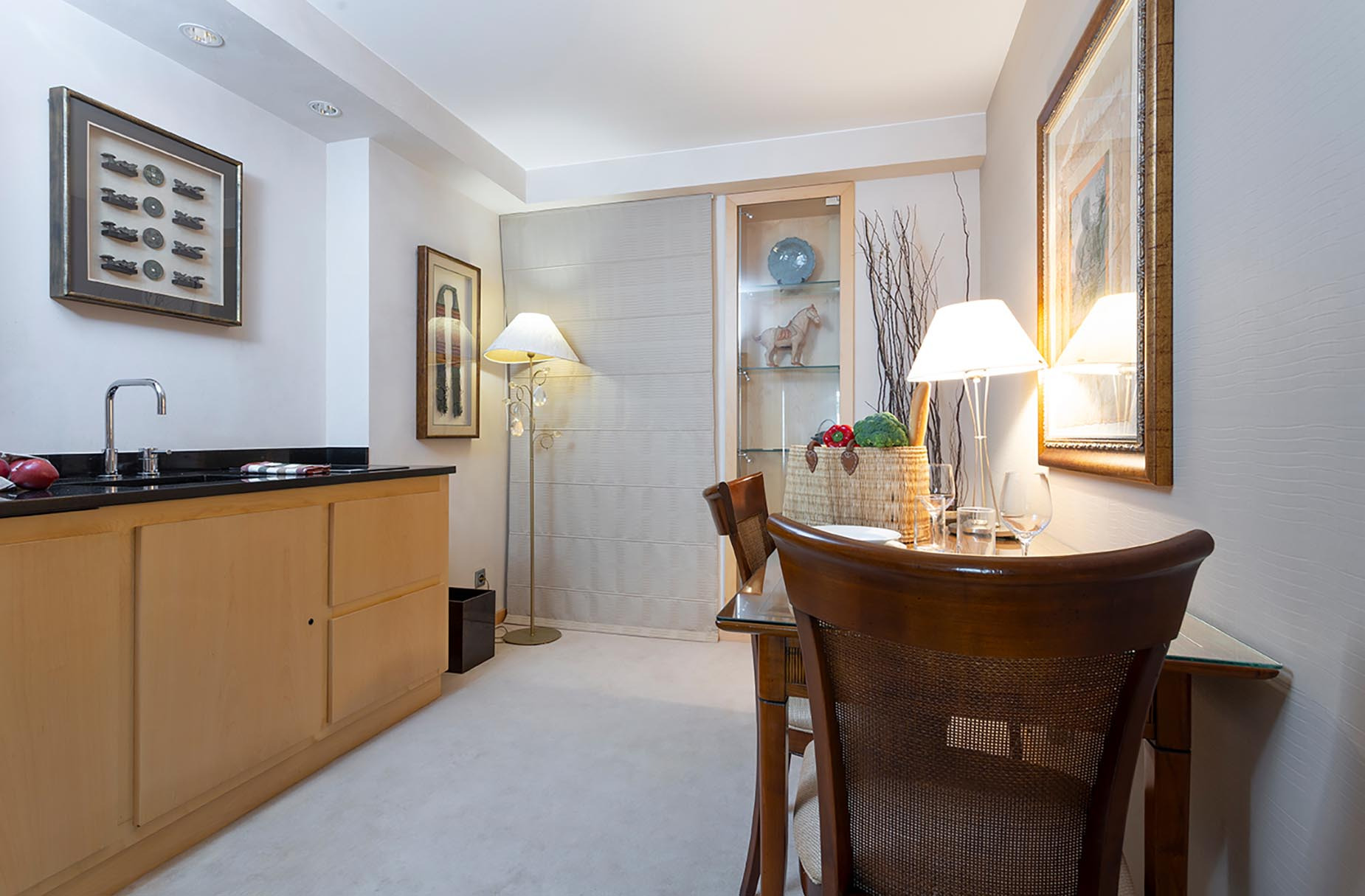 Elegant hotel room with kitchenette, dining table, and art. Suites del Mar Fenals Apartments