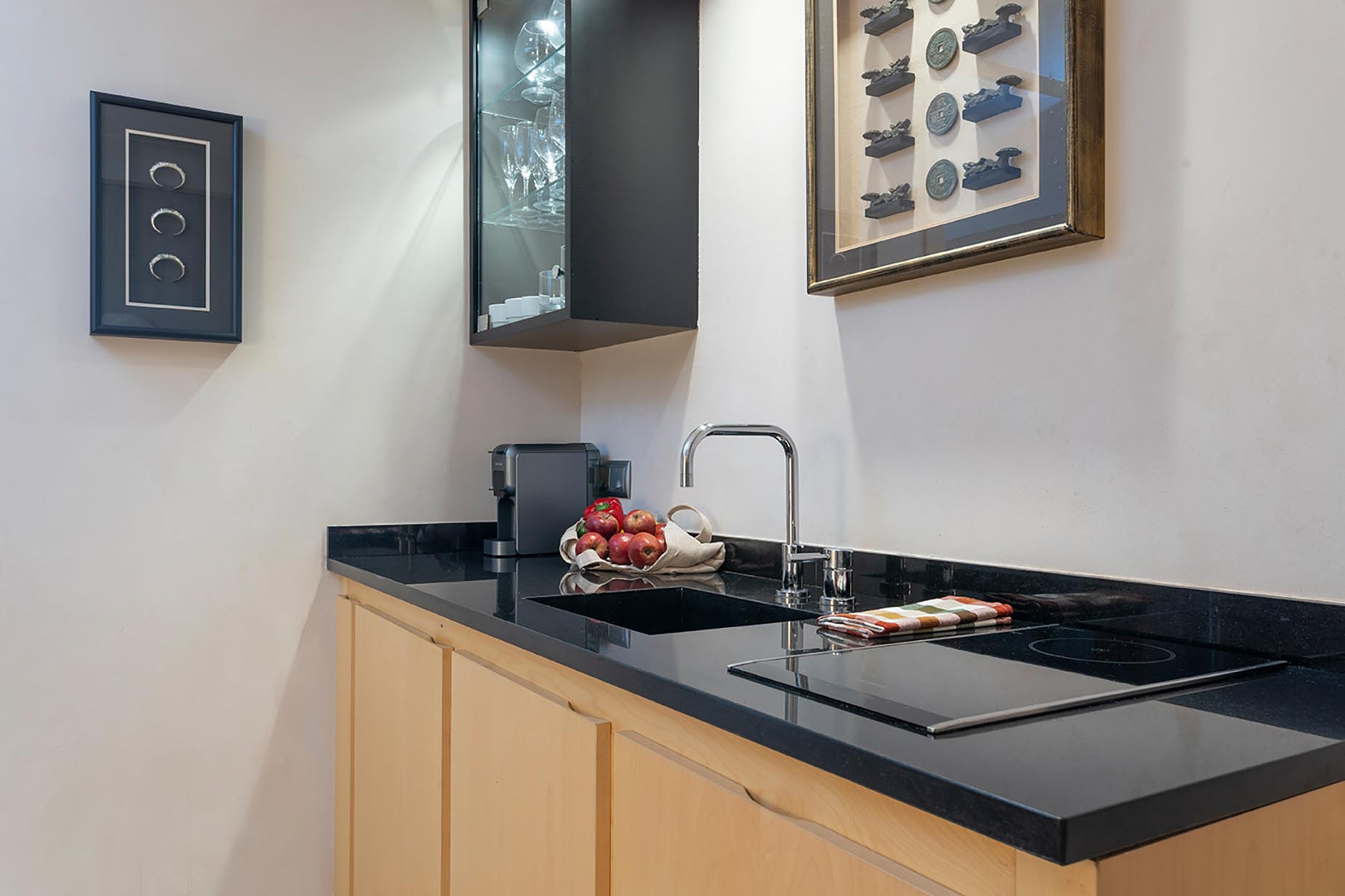 Modern kitchen with granite countertops, sleek sink, and induction cooktop. Suites del Mar Fenals Apartments