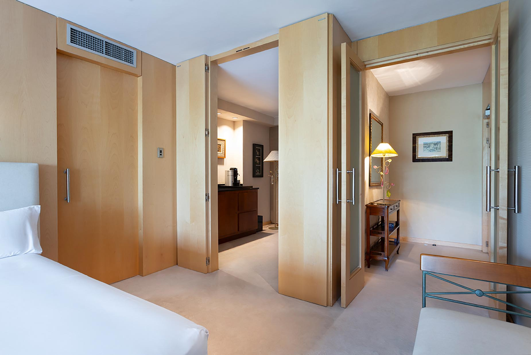 Spacious hotel suite with wooden doors, a bed, and a small living area Suites del Mar Fenals Apartments.