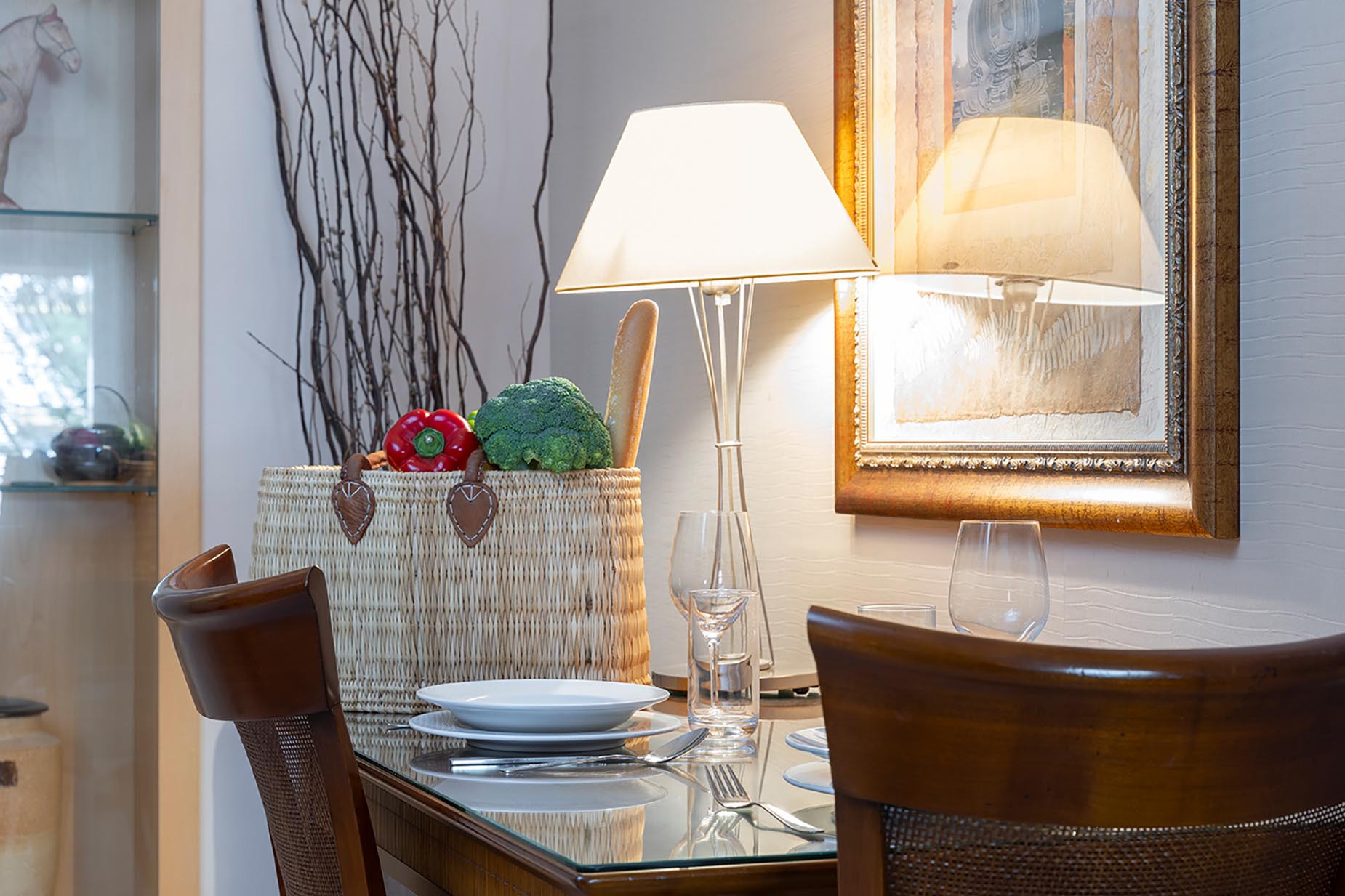 Elegant dining area with a lamp, basket of produce, and artwork, perfect for a relaxing Suites del Mar Fenals Apartments stay.