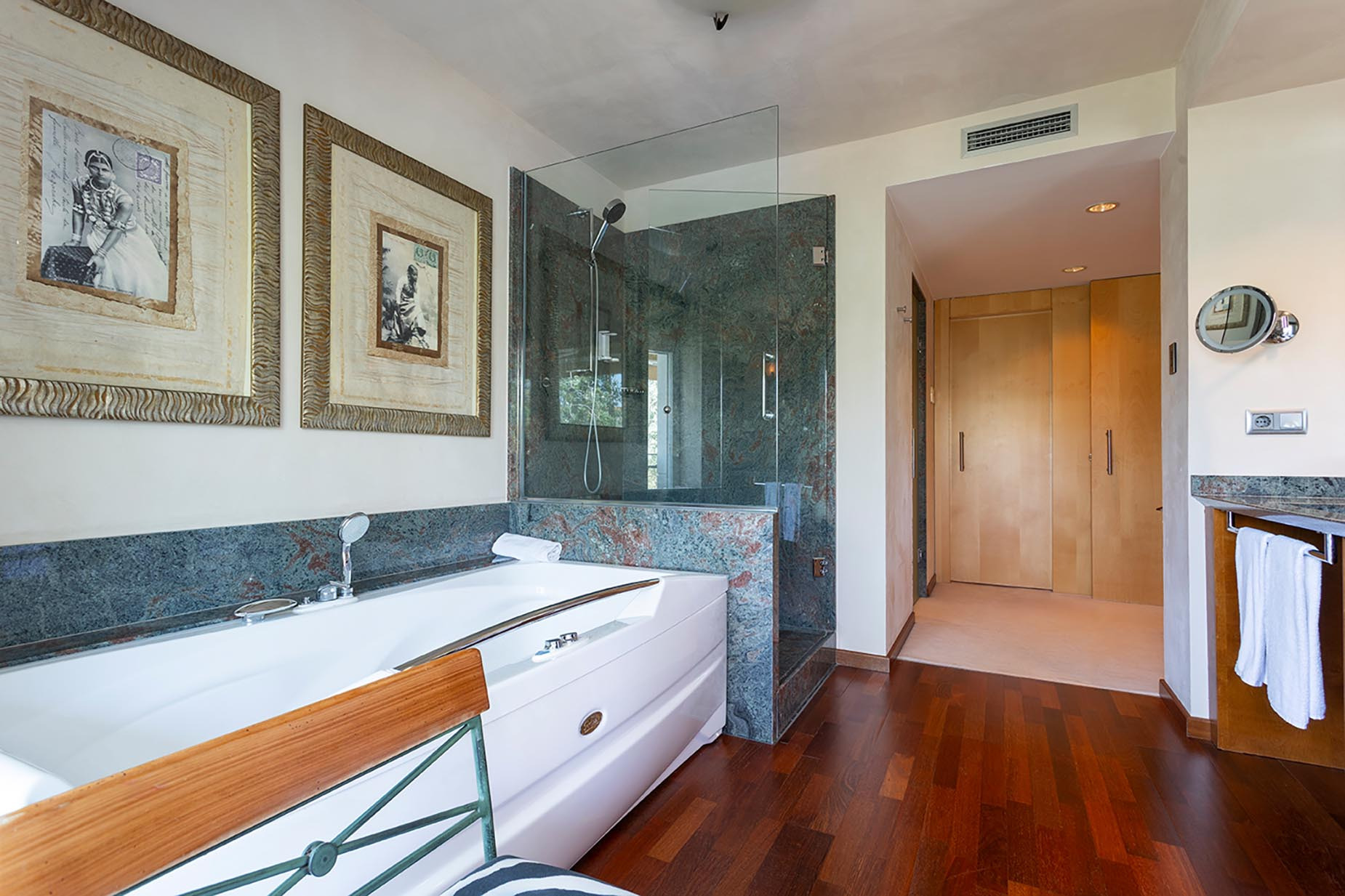 Luxury bathroom with jacuzzi tub, glass shower, and ornate artwork. Suites del Mar Fenals Apartments