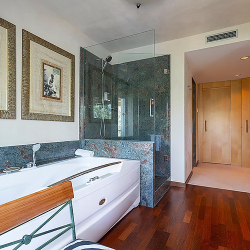 Salle de bain de luxe avec jacuzzi, douche en verre et placards en bois. Suites del Mar Fenals Apartments