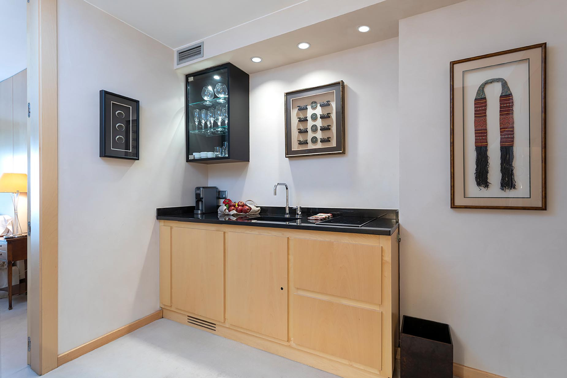 Wet bar with a sink, coffee maker, glassware, and decorative art. Suites del Mar Fenals Apartments.