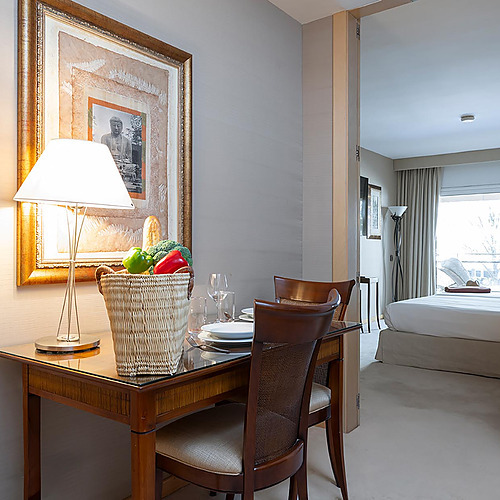 Salle à manger et chambre d'hôtel avec Suites del Mar Fenals Apartments, lit spacieux, art et panier de nourriture.
