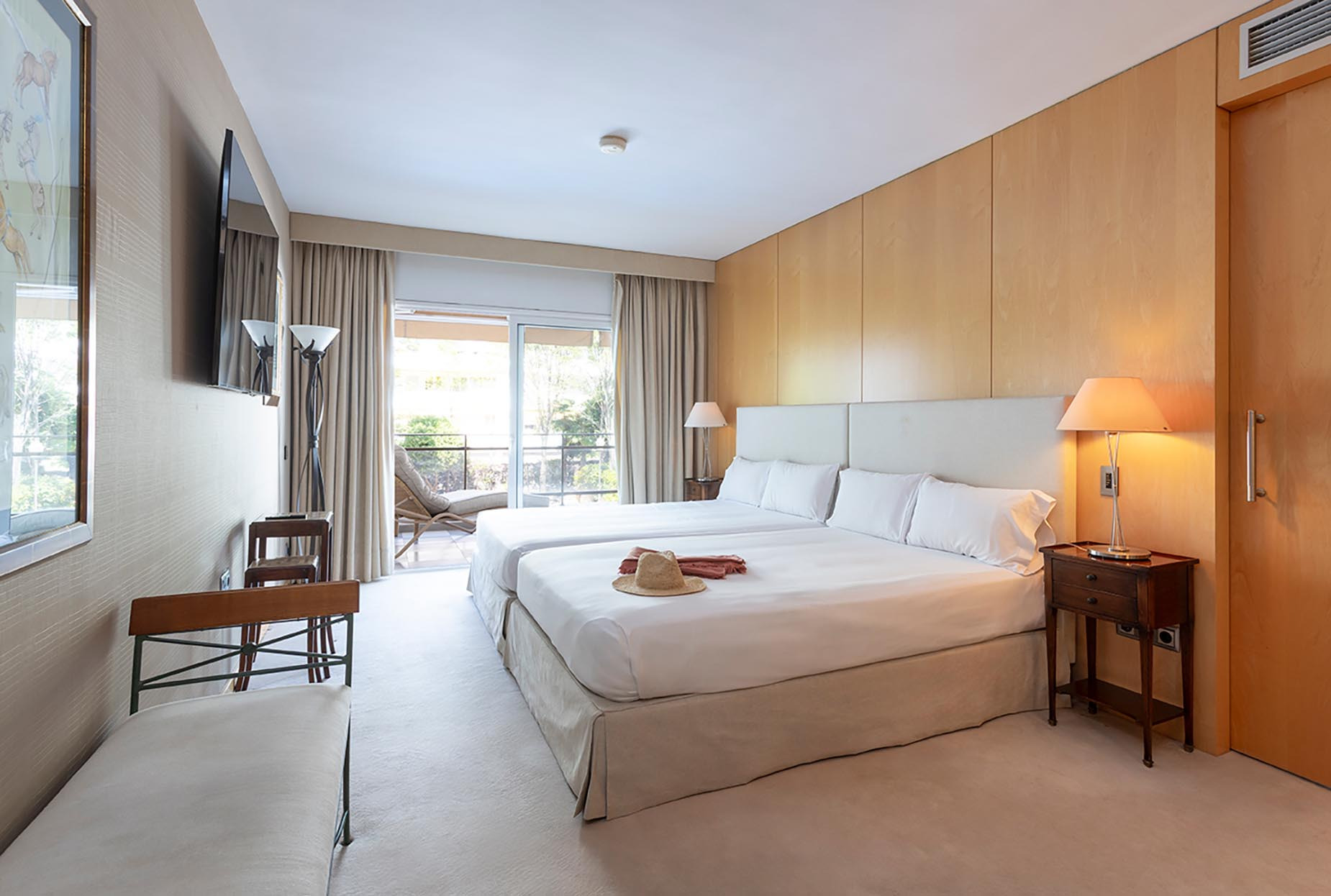Habitación doble luminosa en Suites del Mar Fenals Apartments con balcón y obras de arte.