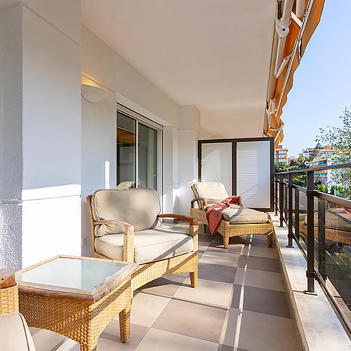 Terrasse de l'hôtel avec Suites del Mar Fenals Apartments, meubles en osier et vue sur la ville.