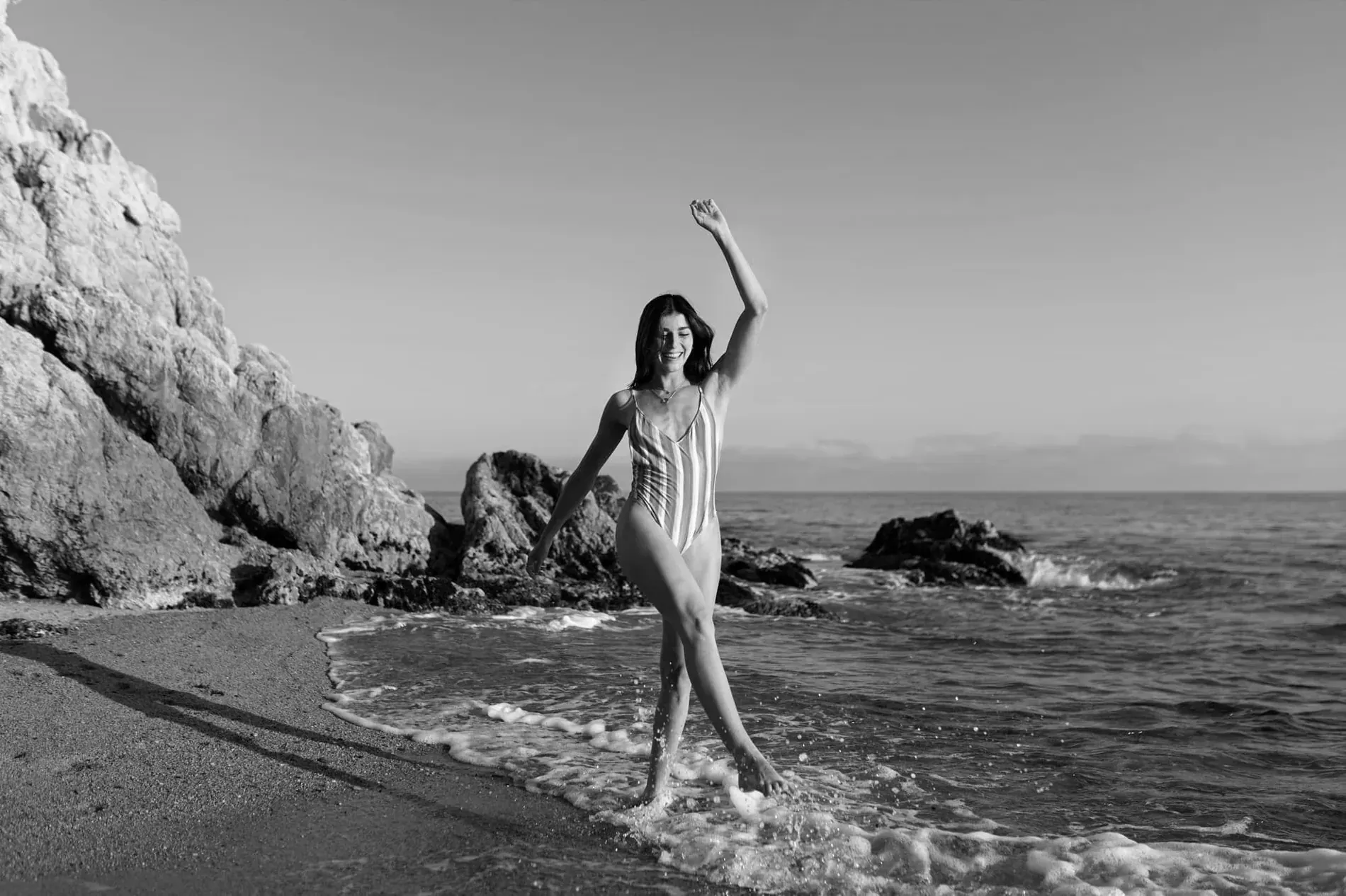 Young woman in striped swimsuit enjoys Maria del Mar beach=s1900