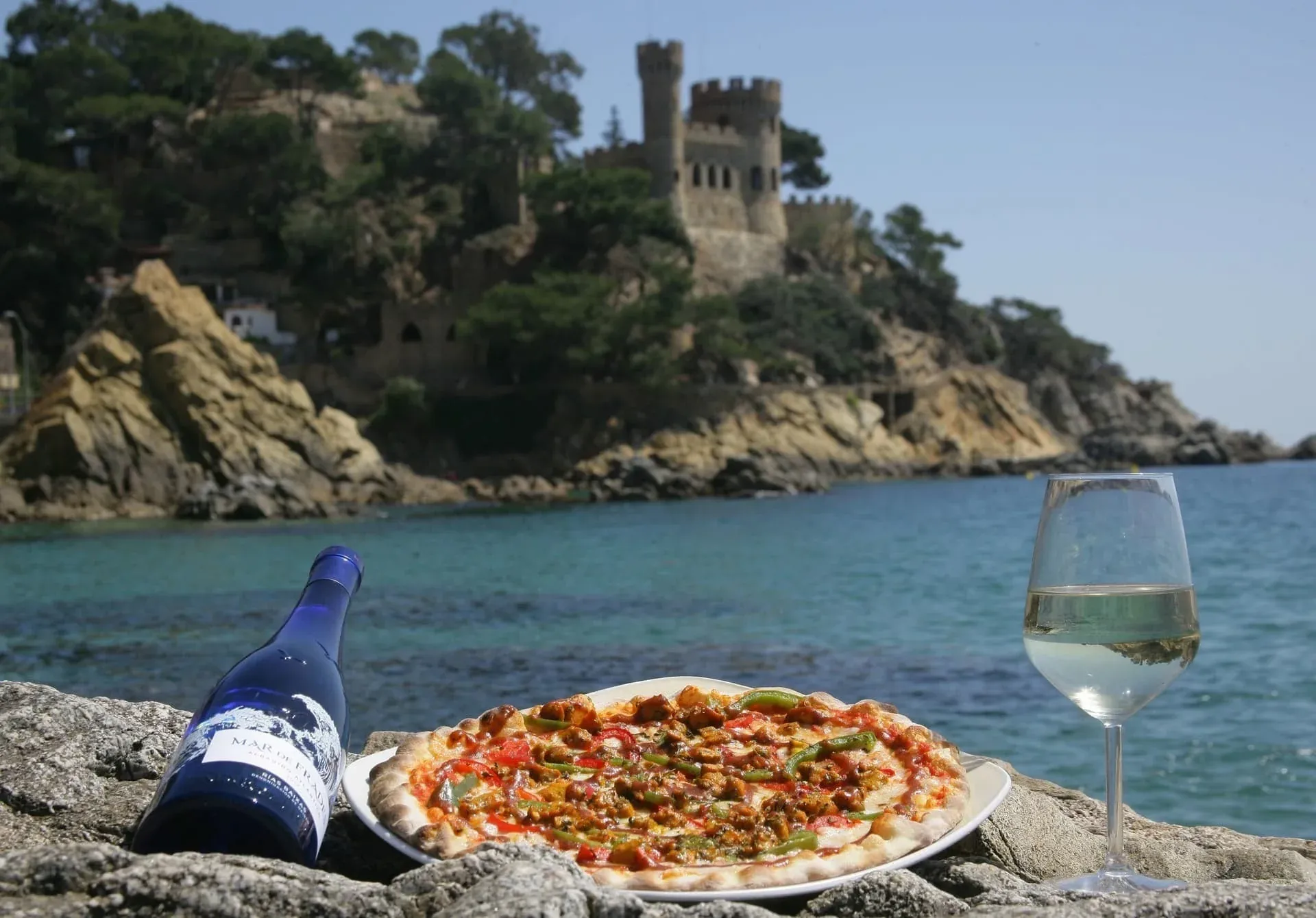 Gaudeix pizza i vi a la platja Maria del Mar, amb castell medieval.