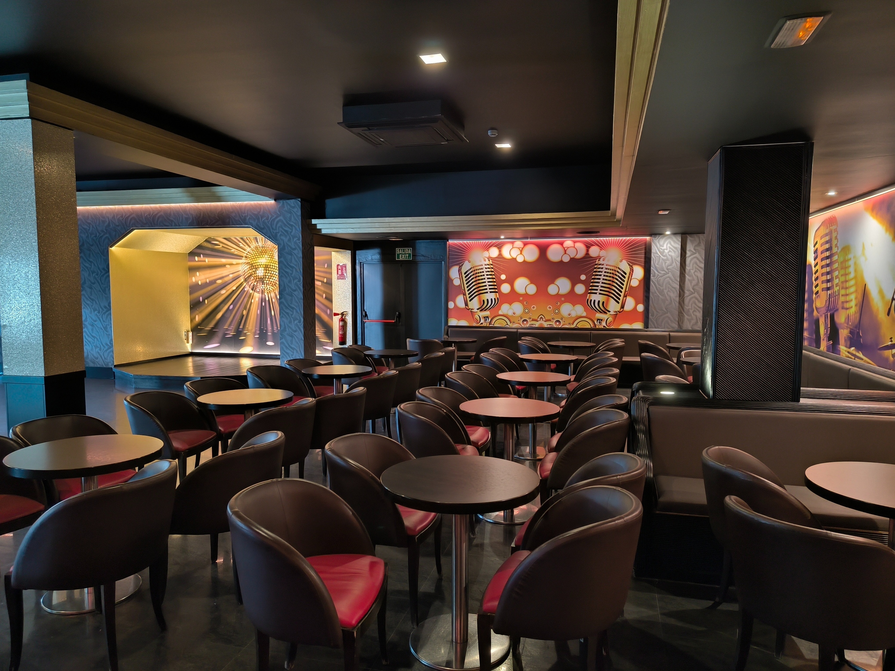 una sala llena de mesas y sillas con micrófonos en la pared