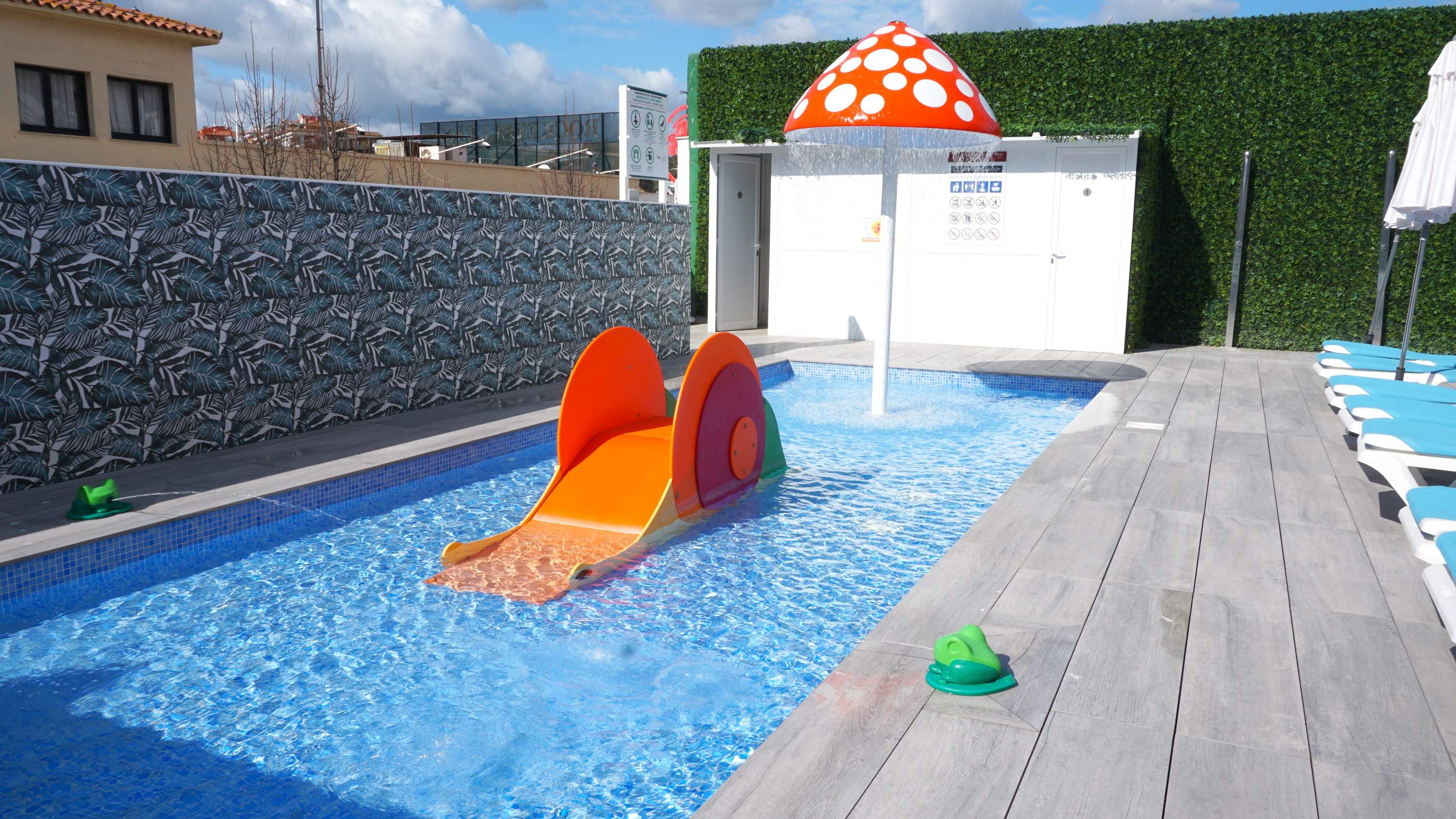 Tobogan infantil i bany al costat d'una piscina amb gandules a un hotel, ideal per a famílies a Maria del Mar.